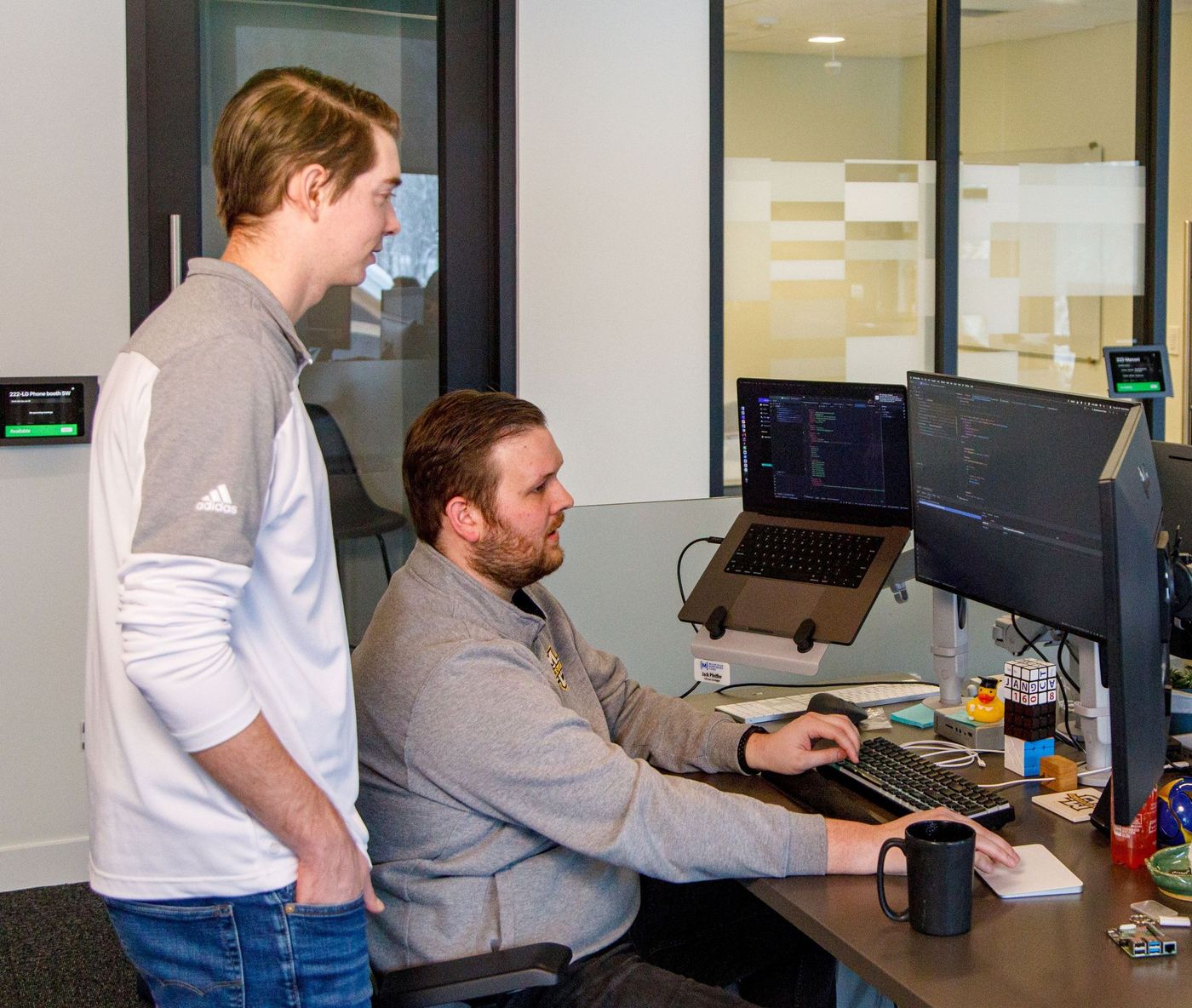 two male developers review their desktop screens