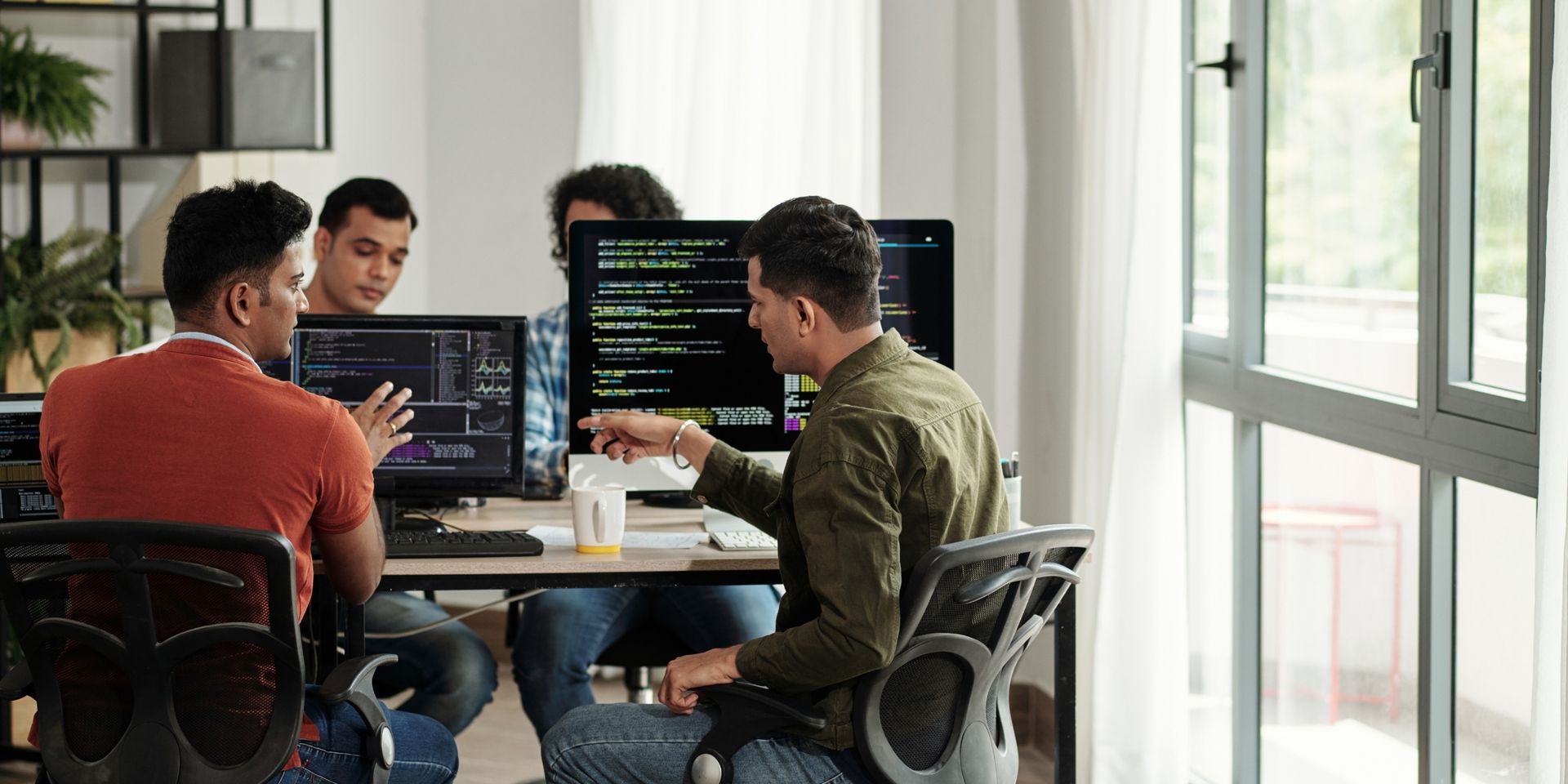four developers review code on their screens