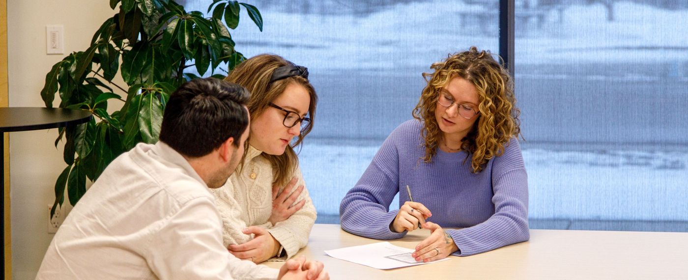 3 people sitting around a table in an office