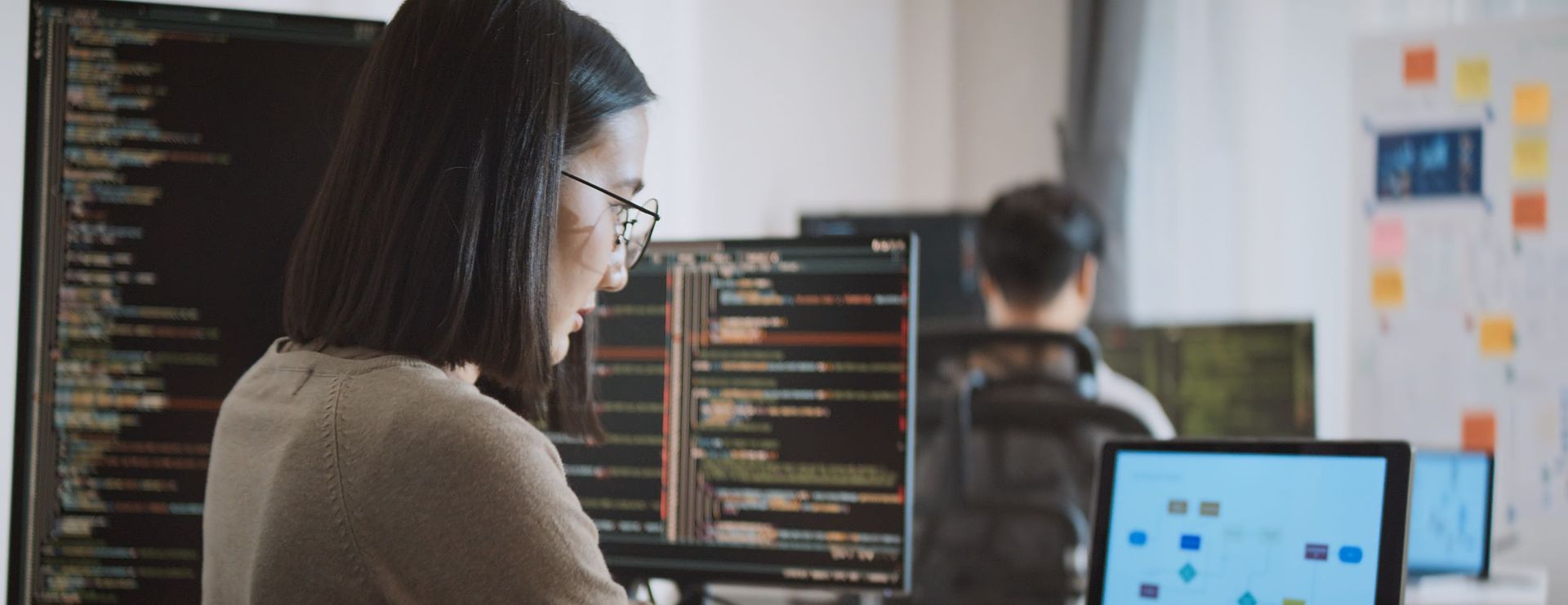 female developer works on multiple computer screens
