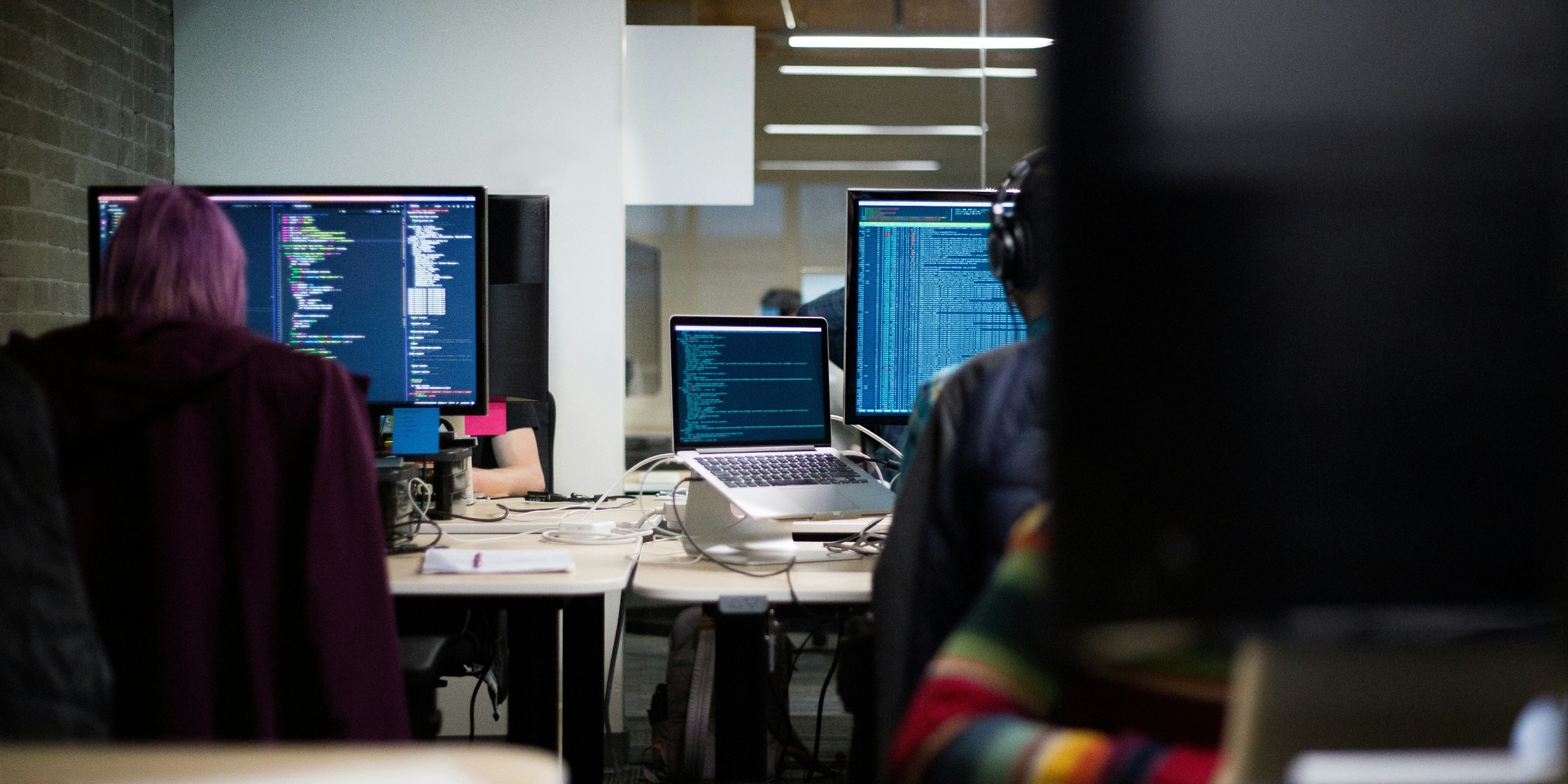 User sitting at desk typing into a MacBook computer